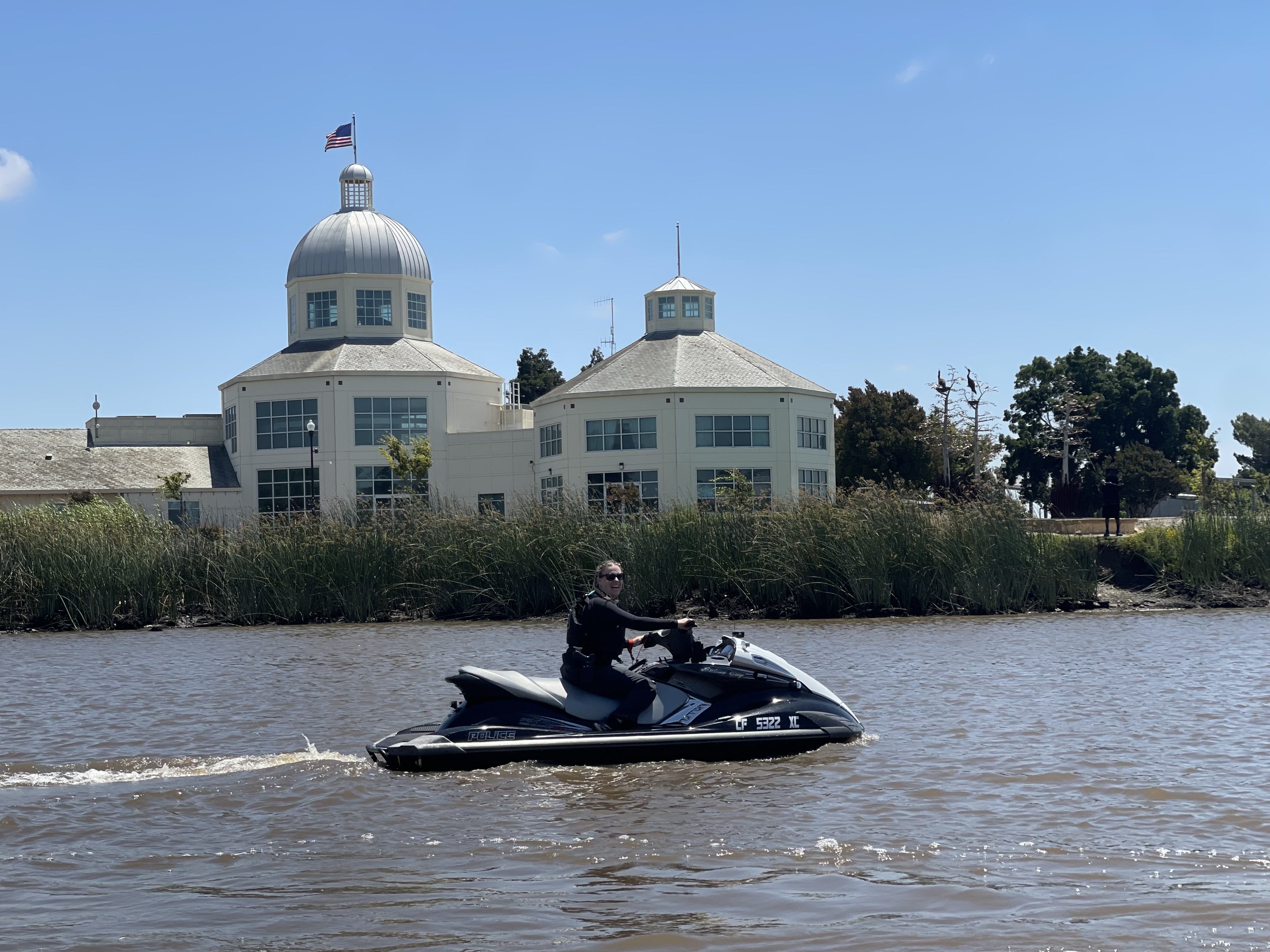 A Boat Patrol Officer on a jet ski with Suisun City Hall in the background.